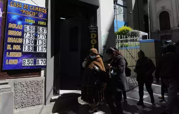 Los peatones pasan junto a una casa de cambio en la capital boliviana de La Paz el 10 de marzo. [Jorge Bernal/AFP]