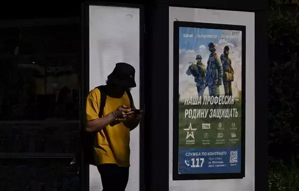 
Un hombre pasa junto a un cartel que promociona el servicio militar por contrato y que dice "Nuestro trabajo, defender la patria" en Moscú el 4 de septiembre. [Natalia Kolesnikova/AFP]        