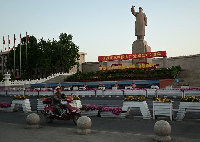 Un hombre pasa en motocicleta junto a un monumento en honor al ex líder chino Mao Zedong en Kasgar, región de Sinkiang, China, el 13 de julio. [Pedro Pardo/AFP]