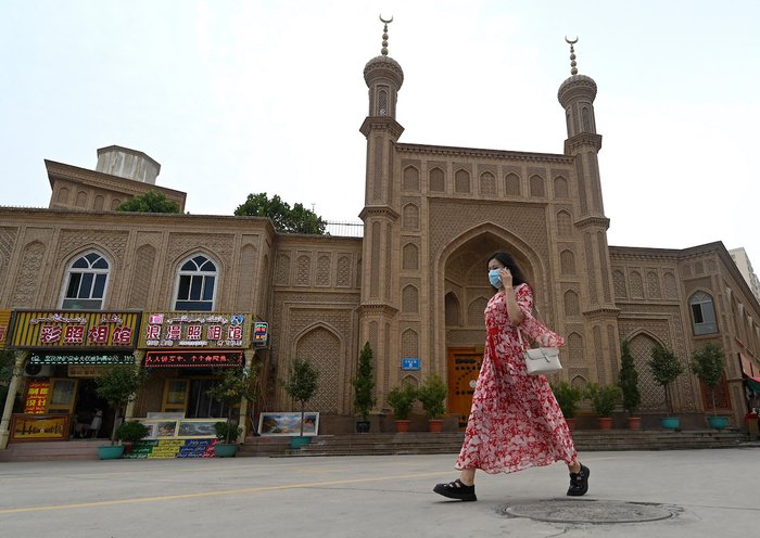 Una mujer pasa al lado de una mezquita vieja en desuso en la región de Sinkiang, China, el 20 de julio. [Pedro Pardo/AFP]