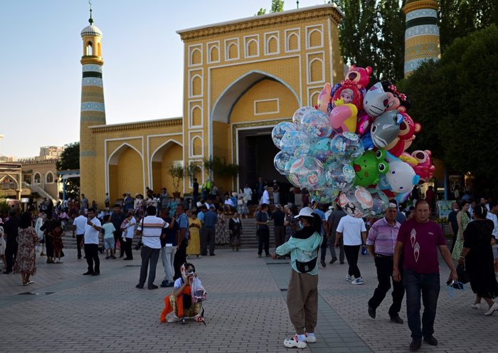 Turistas y vendedores ambulantes se reúnen en la plaza principal frente a la mezquita Id Kah en Kasgar, región de Sinkiang, China, el 13 de julio. [Pedro Pardo/AFP]