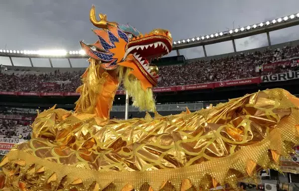 Los artistas ejecutan una danza del dragón mientras celebran el Año Nuevo chino antes de un partido de fútbol del Torneo Argentino de Primera División entre River Plate y Banfield en Buenos Aires en 2020. [Alejandro Pagni/AFP]