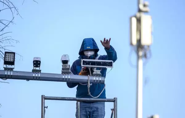 Un trabajador instala cámaras de televisión de circuito cerrado en Pekín. [Noel Celis/AFP]