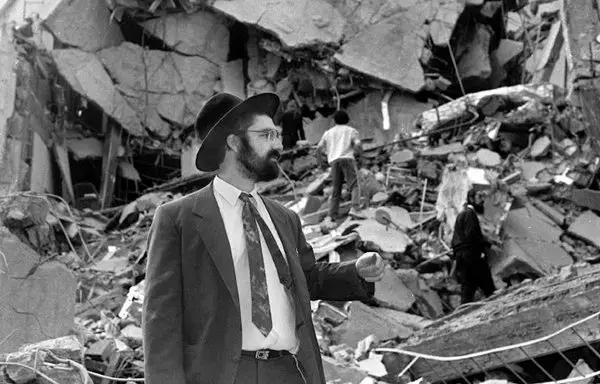 A man walks over the rubble left after a bomb exploded at the Argentinian Israeli Mutual Association (AMIA in Spanish) in Buenos Aires, 18 July 1994. (Photo by Ali Burafi / AFP)