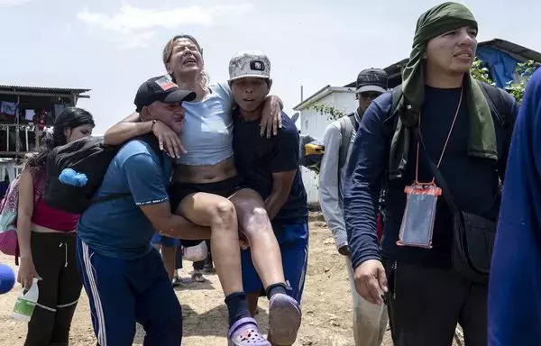 
Migrantes ayudan a una mujer migrante herida en la rodilla en la aldea de Bajo Chiquito, el primer control fronterizo de la provincia de Darién en Panamá, el 22 de septiembre de 2023. [Luis Acosta / AFP]        