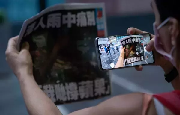 
Una mujer toma una fotografía de la última edición del periódico Apple Daily en el distrito central de Hong Kong el 24 de junio de 2021, después de que el tabloide prodemocracia se viera obligado a cerrar. [Bertha Wang/AFP]        