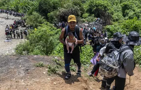 Un migrante y su bebé viajan por la jungla cerca de la aldea de Bajo Chiquito, el primer puesto de control fronterizo de la provincia de Darién, Panamá. El peligroso viaje a través del Tapón del Darién dura unos cinco o seis días y está plagado de peligros que incluyen follaje denso, peligrosos ríos y humedad sofocante. El paso se ve agravado por la presencia de bandas de traficantes de personas, lo que aumenta la cantidad de desafíos en el viaje. [Luis Acosta/AFP]