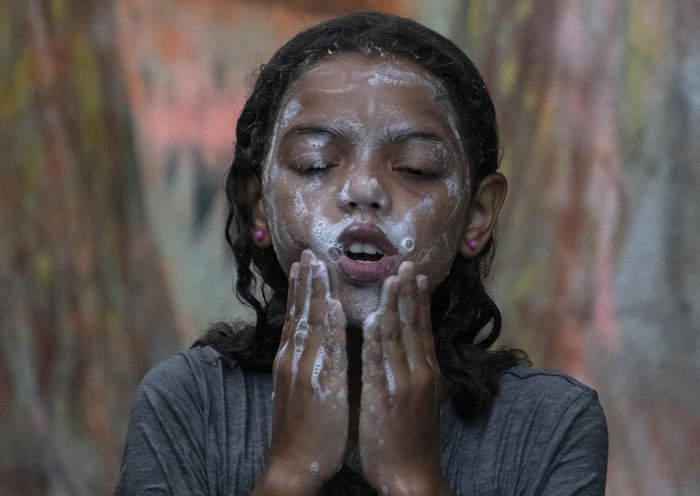 Una niña migrante venezolana se baña bajo la lluvia en un refugio improvisado en Paso Canoas, a unos 300 kilómetros al sur de San José. Un flujo cada vez mayor de migrantes llega cada día a la localidad de Paso Canoas, principal paso fronterizo entre Panamá y Costa Rica, maltrechos tras cruzar la selva del Darién en su camino hacia Estados Unidos. [Ezequiel Becerra / AFP]