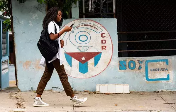 Una mujer camina junto a un muro grafiteado con los Comités de Defensa de la Revolución (CDR) en La Habana. [Yamil Lage / AFP]