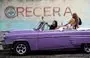 
Turistas posan para un selfie en un viejo auto americano frente a una pared con un graffiti de los Comités de Defensa de la Revolución (CDR) en La Habana. [Yamil Lage / AFP]        