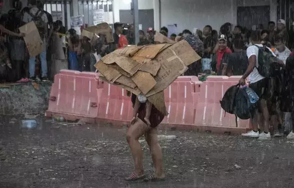 Una inmigrante y su bebé se protegen de la lluvia con cartones en un refugio improvisado en Paso Canoas, a unos 300 km al sur de San José, Costa Rica. [Ezequiel Becerra/AFP].