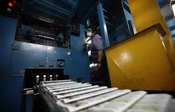 
Un trabajador examina las copias impresas en una fábrica de periódicos en Buenos Aires, Argentina. [Emiliano Lasalvia / AFP]        