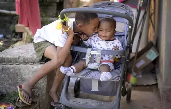 Miguel Barros, de once años, que llamó a la policía por hambre, juega con su hermano menor Gael en su casa de Belo Horizonte, Brasil. Los brasileños se movilizaron para donar alimentos a su familia. [Douglas Magno/AFP]