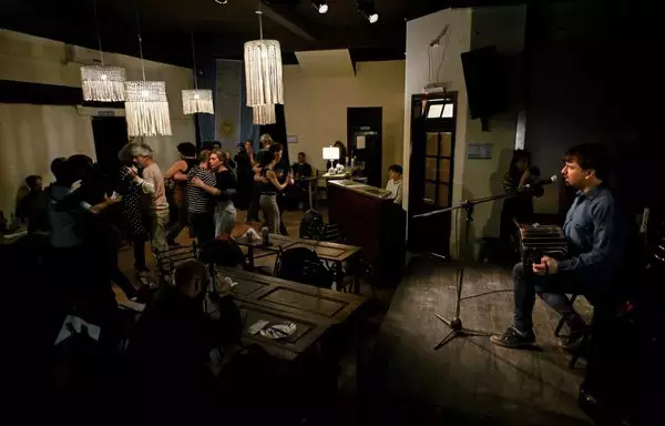 Bandoneonist Julio Coviello and pianist Nicolas Di Lorenzo (out of frame), members of the contemporary tango group Duo Cañon, serenade tango aficionados as they dance at the milonga "Cañon" in La Tierra Invisible tango nightclub in Buenos Aires. [Luis Robayo / AFP]