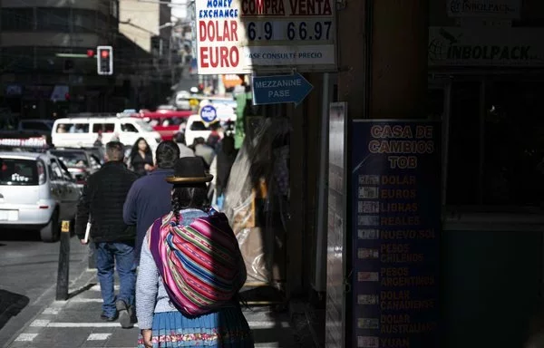 Una mujer indígena aymara pasa junto a una casa de cambio en La Paz. Bolivia está lidiando con una escasez crónica de combustible y una escasez de dólares, lo que hace subir los tipos de cambio en el mercado paralelo. [Ernesto Benavides/AFP]