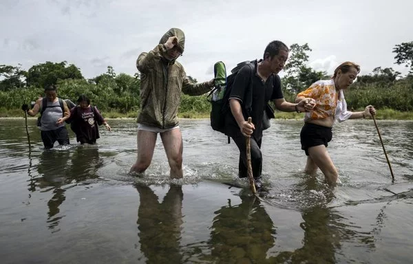 Migrantes que se atreven a cruzar el Tapón del Darién atraviesan el río Tuquesa cerca de la aldea de Bajo Chiquito, el primer puesto de control fronterizo de la provincia del Darién, Panamá, en septiembre pasado. [Luis Acosta/AFP]