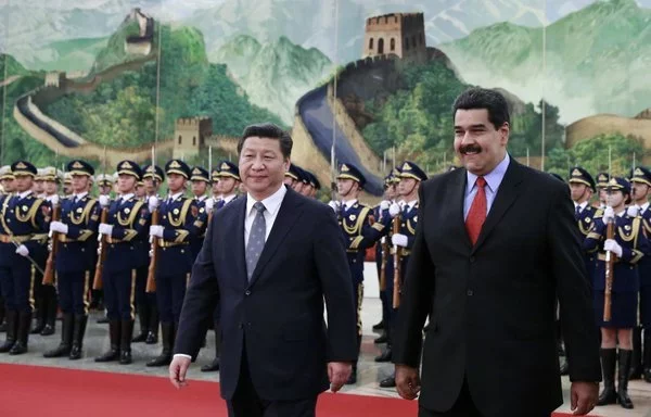 El presidente venezolano, Nicolás Maduro, y el presidente chino, Xi Jinping, caminan tras haber pasado revista a una guardia de honor en Pekín en enero de 2015. Maduro pidió entonces una nueva inyección de liquidez para apuntalar la economía venezolana. [Andy Wong/AFP]