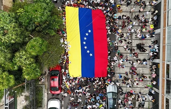 Venezolanos residentes en México sostienen la bandera de Venezuela frente a la embajada de su país en la Ciudad de México, el 28 de julio. [Alfredo Estrella/AFP]