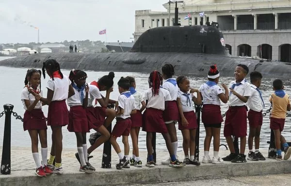 Un grupo de jóvenes pioneros cubanos observa el submarino nuclear Kazán, parte del destacamento naval ruso que visita Cuba y atracó en La Habana el 14 de junio. [Yamil Lage/AFP]