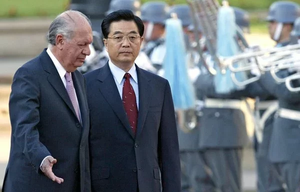 El entonces presidente chileno Ricardo Lagos (izq.) y el entonces presidente chino Hu Jintao participan en una ceremonia en la Plaza Constitución de Santiago en noviembre de 2004. Durante su visita, Hu anunció el inicio de las negociaciones para el TLC chino-chileno, que entró en vigor en 2005. [Rodrigo Arangua/AFP]