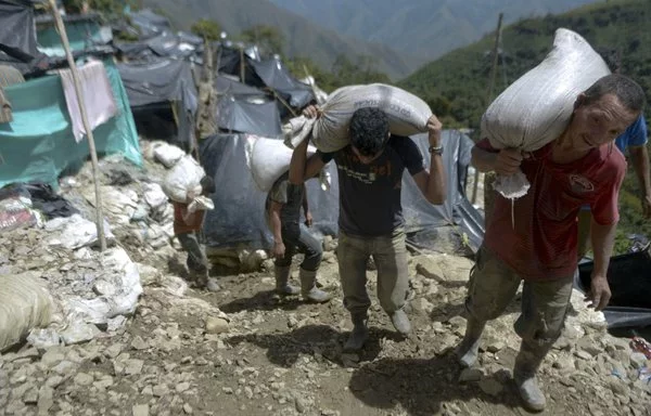 Mineros cargan sacos de rocas cargadas de oro de una mina sin licencia en el pueblo de San Antonio, cerca de Buriticá, Colombia. El conglomerado chino Zijin Mining Group ha sido acusado de violar los derechos de los trabajadores. [Raúl Arboleda/AFP]