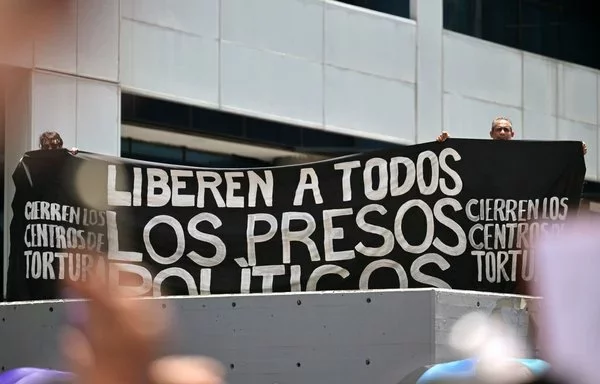 Manifestantes con una pancarta que pide libertad para los presos políticos durante una marcha en Caracas. [Juan Barreto/AFP]