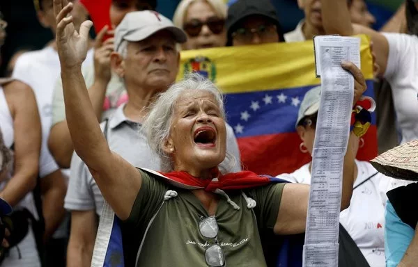 Una mujer grita consignas con actas electorales en la mano durante una manifestación convocada por la oposición en Caracas. [Pedro Rances Mattey/AFP]