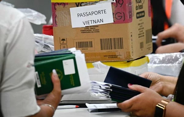 Funcionarios del Aeropuerto Internacional de Guarulhos controlan los pasaportes de pasajeros de Vietnam e India varados en Sao Paulo, Brasil. [Juan Pablo Flores/AFP]