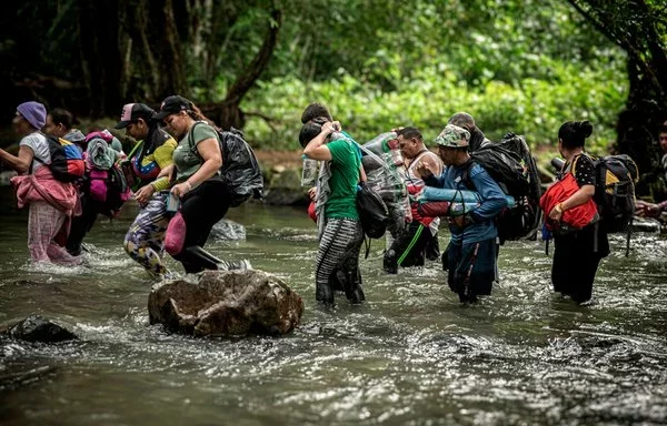 Migrantes caminan por un río mientras cruzan el peligroso Tapón del Darién. [Médicos Sin Fronteras]