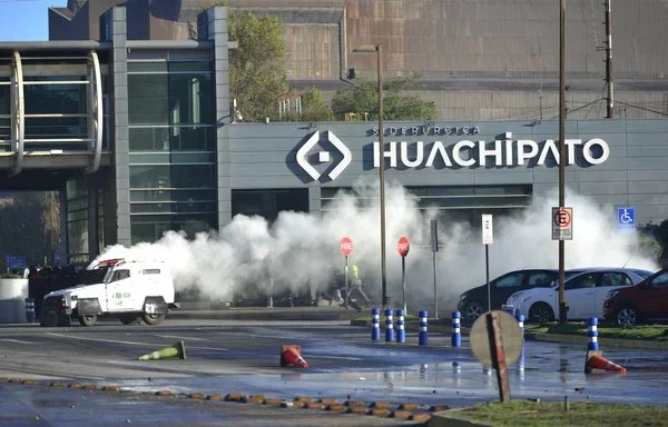 
Trabajadores del acero se enfrentan con la policía antidisturbios durante una protesta contra el cierre de la planta siderúrgica de Huachipato en Talcahuano, Chile. El cierre se atribuye a la importación masiva de acero chino, que cuesta un 40% menos que el acero local. [Guillermo Salgado/AFP]        