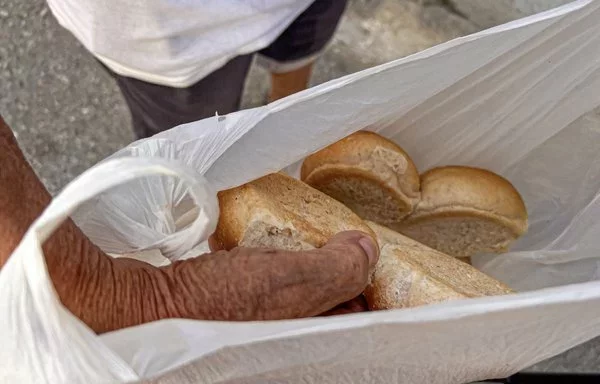 Un hombre muestra la ración diaria de pan para su familia en La Habana. Los ciudadanos cubanos están recibiendo hogazas de pan más pequeñas, menos arroz y nada de aceite y café para este mes, dejando claras las dificultades acumuladas en el suministro de alimentos subsidiados, otra señal de la profundización de la crisis en la isla. [Adalberto Roque/AFP]