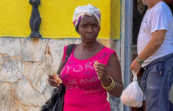 Una mujer come el pan de cada día frente a una panadería en La Habana. [Adalberto Roque/AFP]