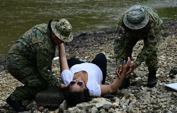 La Policía del Senafront panameño ayuda a la migrante venezolana Marisol Jaime a su llegada al Centro de Acogida Temporal de Migrantes en Lajas Blancas, en la selvática provincia de Darién, 250 kilómetros al este de la ciudad de Panamá. [Martín Bernetti/AFP]