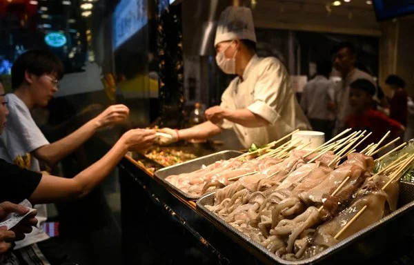 Los clientes compran calamares fritos en una pequeña tienda de Shanghai. [Héctor Retamal/AFP]