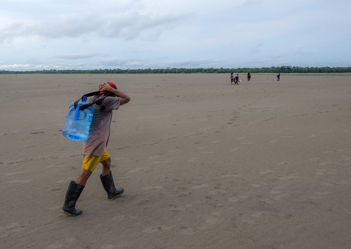 Un indígena yagua transporta agua y otros bienes después de que gran parte del río Amazonas se secó en la isla de los Micos, Colombia. [Luis Acosta/AFP]