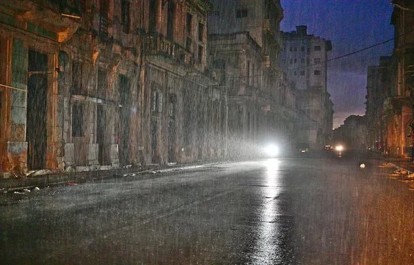 
Una motocicleta ilumina la calle bajo una lluvia torrencial durante el apagón nacional causado por un fallo de la red eléctrica en La Habana el 19 de octubre. [Adalberto Roque/AFP]        