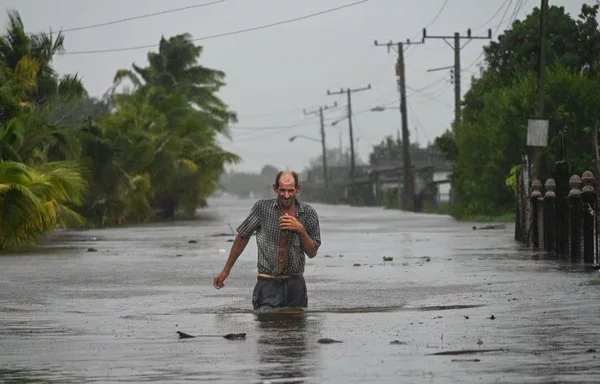 Residentes de la ciudad costera de Guanímar en la provincia de Artemisa, Cuba, al suroeste de La Habana, caminan por una calle inundada tras el paso del huracán Helene el 25 de septiembre. [Yamil Lage/AFP]