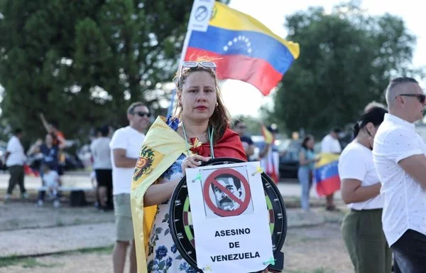 Un partidario sostiene un cartel que llama a Nicolás Maduro el “asesino de Venezuela” en el aeropuerto militar de Torrejón de Ardoz, en Madrid, España, en septiembre. [Thomas Coex/AFP]