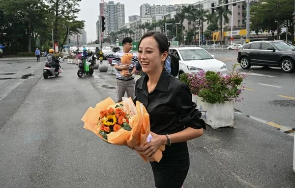 Un grupo de personas lleva ramos de flores a un monumento conmemorativo situado frente al Polideportivo de Zhuhai, en la provincia china de Guangdong, el 13 de noviembre, en homenaje a las 35 víctimas fallecidas dos días antes cuando un hombre arrolló a una multitud en uno de los incidentes con mayor número de víctimas mortales de los últimos años en China. [Hector Retamal/AFP]