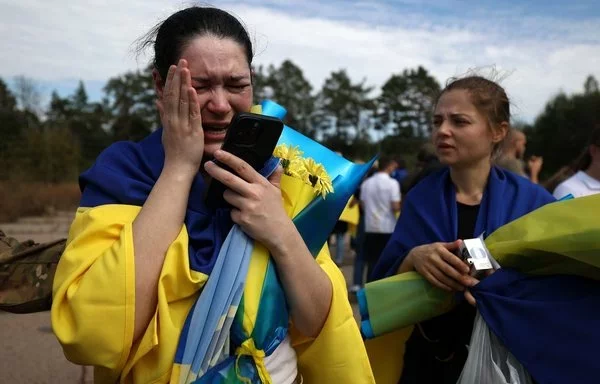 
Una militar ucraniana habla por teléfono con sus hijos después de su liberación del cautiverio ruso en un lugar no revelado cerca de la frontera entre Ucrania y Bielorrusia, el 13 de septiembre. [Anatolii Stepanov/AFP]        