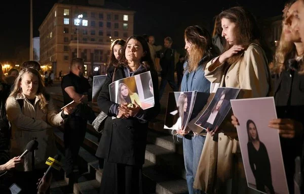 Colegas de la fallecida periodista ucraniana Victoria Roshchyna sostienen fotografías de ella durante un evento en su memoria en un improvisado monumento a los soldados ucranianos caídos en Kiev el 11 de octubre. [Anatolii Stepanov/AFP]