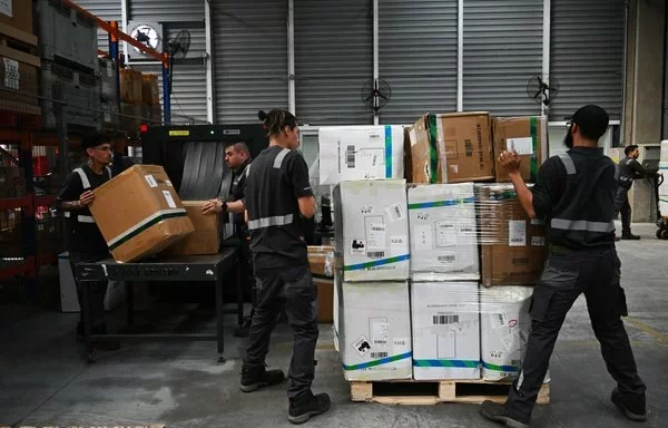 Trabajadores de una empresa naviera organizan paquetes en el Aeropuerto Internacional de Santiago, en noviembre. [Rodrigo Arangua/AFP]