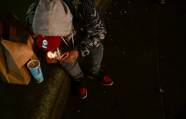 
Un hombre consume fentanilo en Park Avenue, en el centro de Portland, Oregón. [Patrick T. Fallon/AFP]        