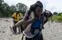 
Una mujer inmigrante camina por la selva cargando a su hija cerca del pueblo de Bajo Chiquito, el primer cruce fronterizo para la provincia de Darién en Panamá. [Luis Acosta/AFP]        