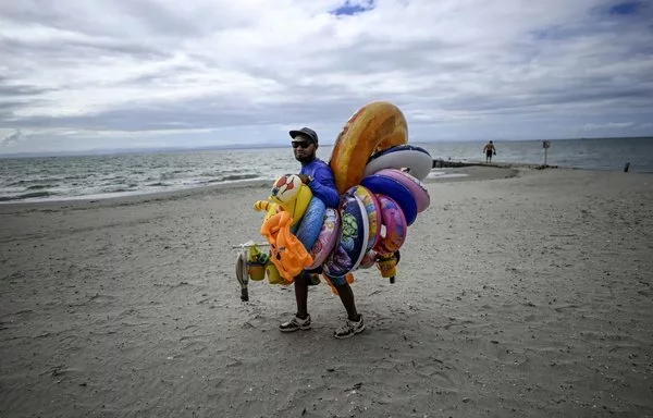 Un vendedor ambulante pasea por la playa de El Yaque en la isla Margarita, Venezuela. Margarita, otrora un paraíso caribeño, se ha enfrentado a un fuerte deterioro como consecuencia de años de turbulencias económicas, una inflación descontrolada, la pandemia y el colapso de los servicios públicos. [Juan Barreto/AFP]