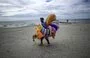 
Un vendedor ambulante pasea por la playa de El Yaque en la isla Margarita, Venezuela. Margarita, otrora un paraíso caribeño, se ha enfrentado a un fuerte deterioro como consecuencia de años de turbulencias económicas, una inflación descontrolada, la pandemia y el colapso de los servicios públicos. [Juan Barreto/AFP]        