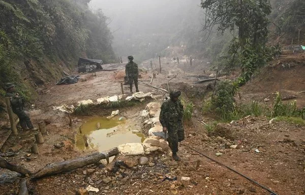 Soldados caminan sobre una mina de oro ilegal destruida en el Parque Natural Farallones, cerca de Cali, Colombia. [Joaquín Sarmiento/AFP]