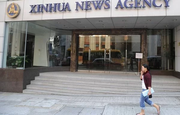 Varios transeúntes pasan por delante de la sede de la agencia de noticias Xinhua en Hong Kong en 2008. [Mike Clarke/AFP]