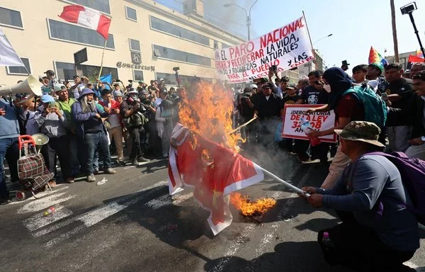 Manifestantes queman una bandera china en una protesta contra la Cumbre de Cooperación Económica Asia-Pacífico (APEC) en Lima, Perú, en noviembre. [Hugo Curotto/AFP]