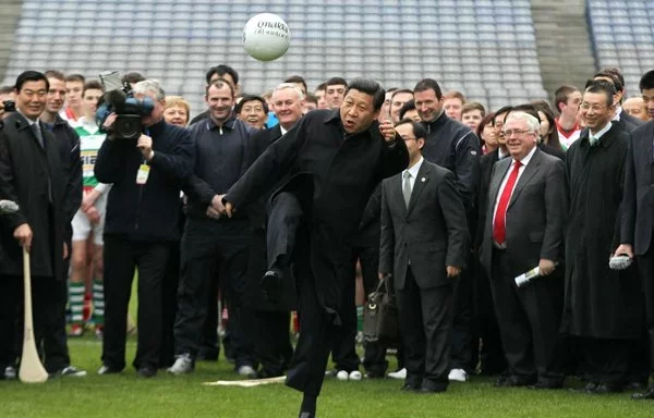 El futuro presidente chino Xi Jinping (centro) patea un balón de fútbol gaélico durante su visita como vicepresidente a Dublín, Irlanda, en febrero de 2012. Allí asistió a una exhibición de fútbol gaélico y hurling. [Peter Muhly/AFP]